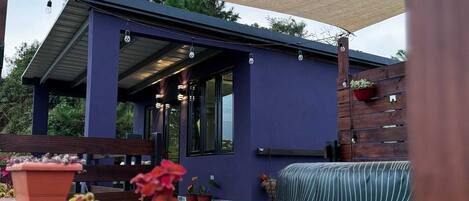 A modern outdoor patio area with a covered seating area, potted plants, and a wooden deck.