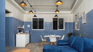 Een compacte woonruimte met een eethoek, kitchenette en een blauwe bank.