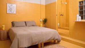 Een slaapkamer met een bed, bedlampen, een potplant en een douchegedeelte.