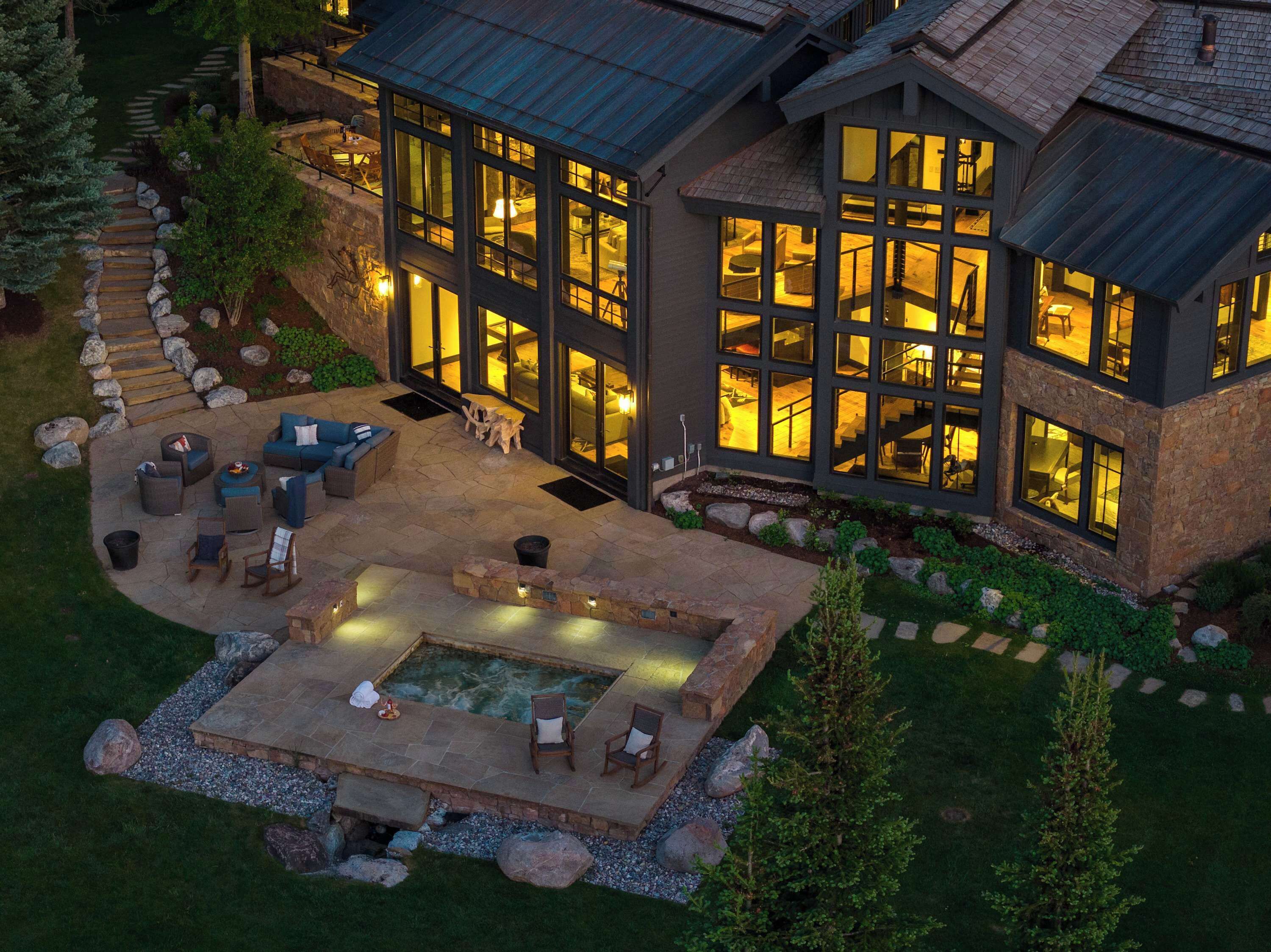 Een modern huis met een ruim terras, buitenmeubels en een jacuzzi.