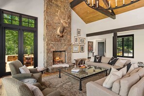 Un salón amplio con chimenea de piedra, asientos cómodos y ventanas grandes.