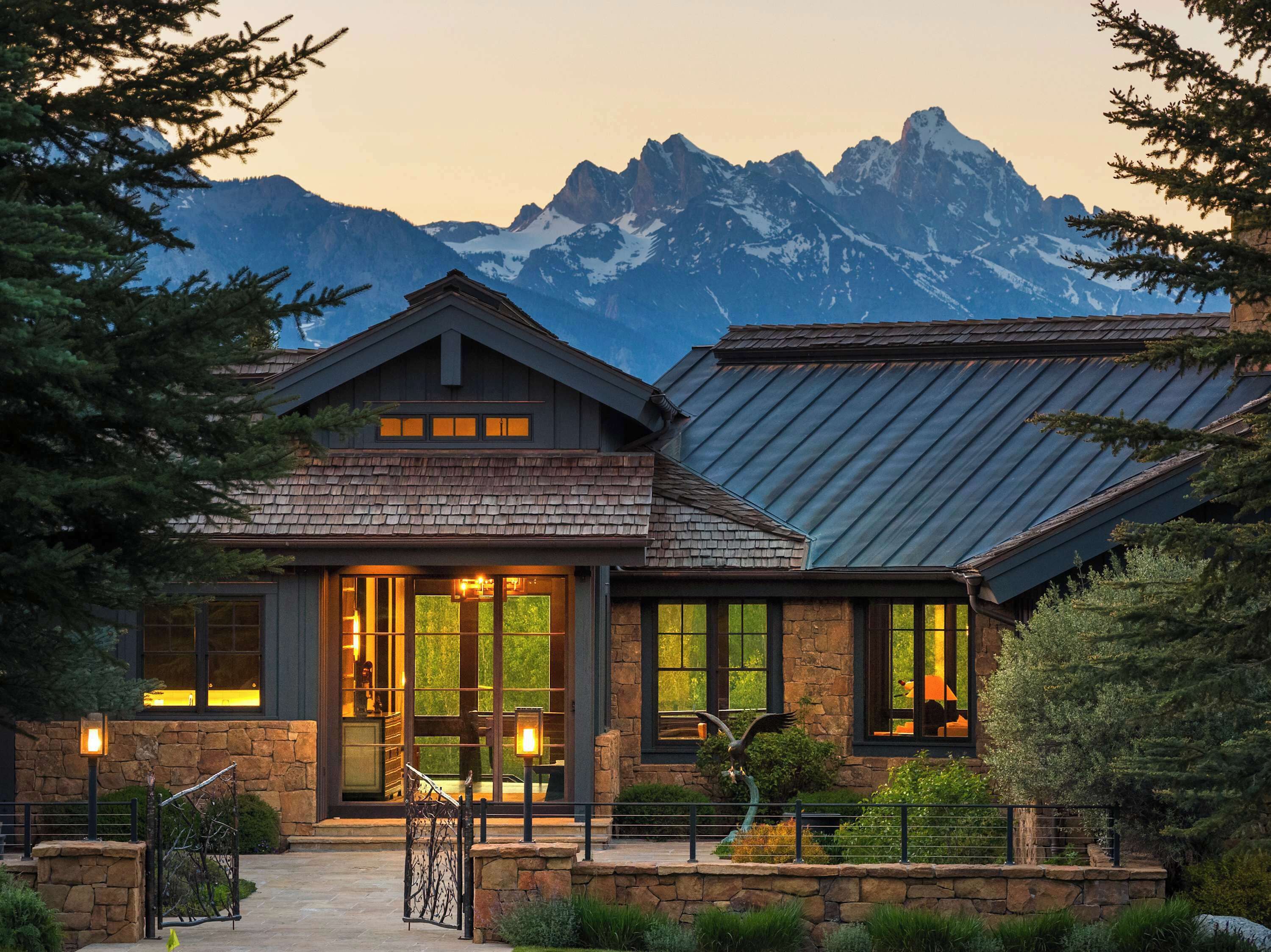 A stone building with large windows and a mountain backdrop.