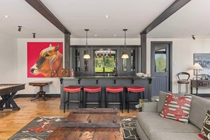 Una cocina moderna con barra, mesa de billar y sofá con cojines decorativos.