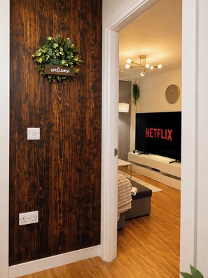 Eine Holztür mit einer Willkommensschild, einer Wanduhr und einem Netflix-Logo.