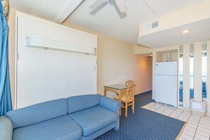 A compact room with a sofa, a small table, and a refrigerator. - Yachtsman S605 1 BR Oceanfront Retreat (Myrtle Beach)