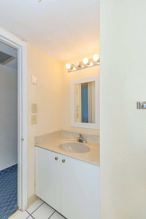 A bathroom with a sink, mirror, and vanity.