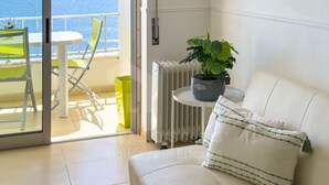 Un balcón con una silla, una mesa y una planta en maceta.