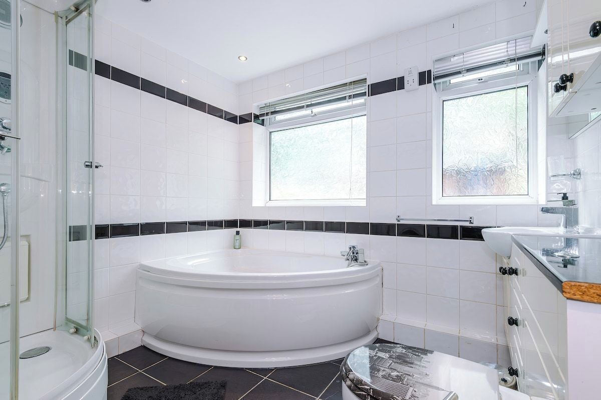 Un baño moderno con una bañera independiente, una cabina de ducha de vidrio y un ventanal que proporciona luz natural.