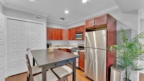 A kitchen with wooden cabinets, stainless steel appliances, a dining table, and a potted plant. - Apartmint at 1149 N 3rd St Philladelphia (Philadelphia)