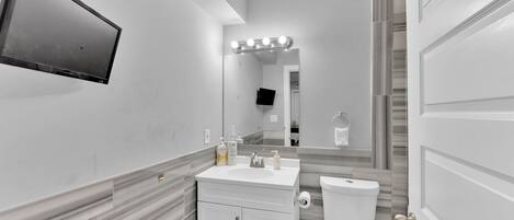 Une salle de bain moderne avec un meuble-lavabo, un évier, un miroir et des toilettes.