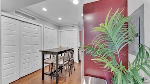 A modern kitchen with white cabinets, a dining table, chairs, and a potted plant. - Apartmint at 1149 N 3rd St Philladelphia (Philadelphia)