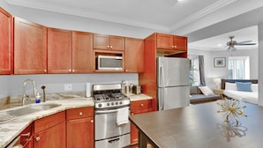 A modern kitchen with wooden cabinets, stainless steel appliances, and a marble countertop. - Apartmint at 1149 N 3rd St Philladelphia (Philadelphia)