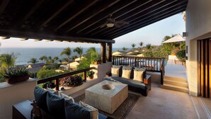 A covered outdoor seating area with a view of the ocean, a stone coffee table, and a sofa with cushions. - Four Seasons Villa Riva | 4BR Ocean-View Retreat w/ Infinity Pool & Golf Cart (Punta Mita)