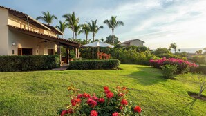 A house with a covered patio, a well-maintained lawn, and palm trees. - Four Seasons Villa Riva | 4BR Ocean-View Retreat w/ Infinity Pool & Golf Cart (Punta Mita)