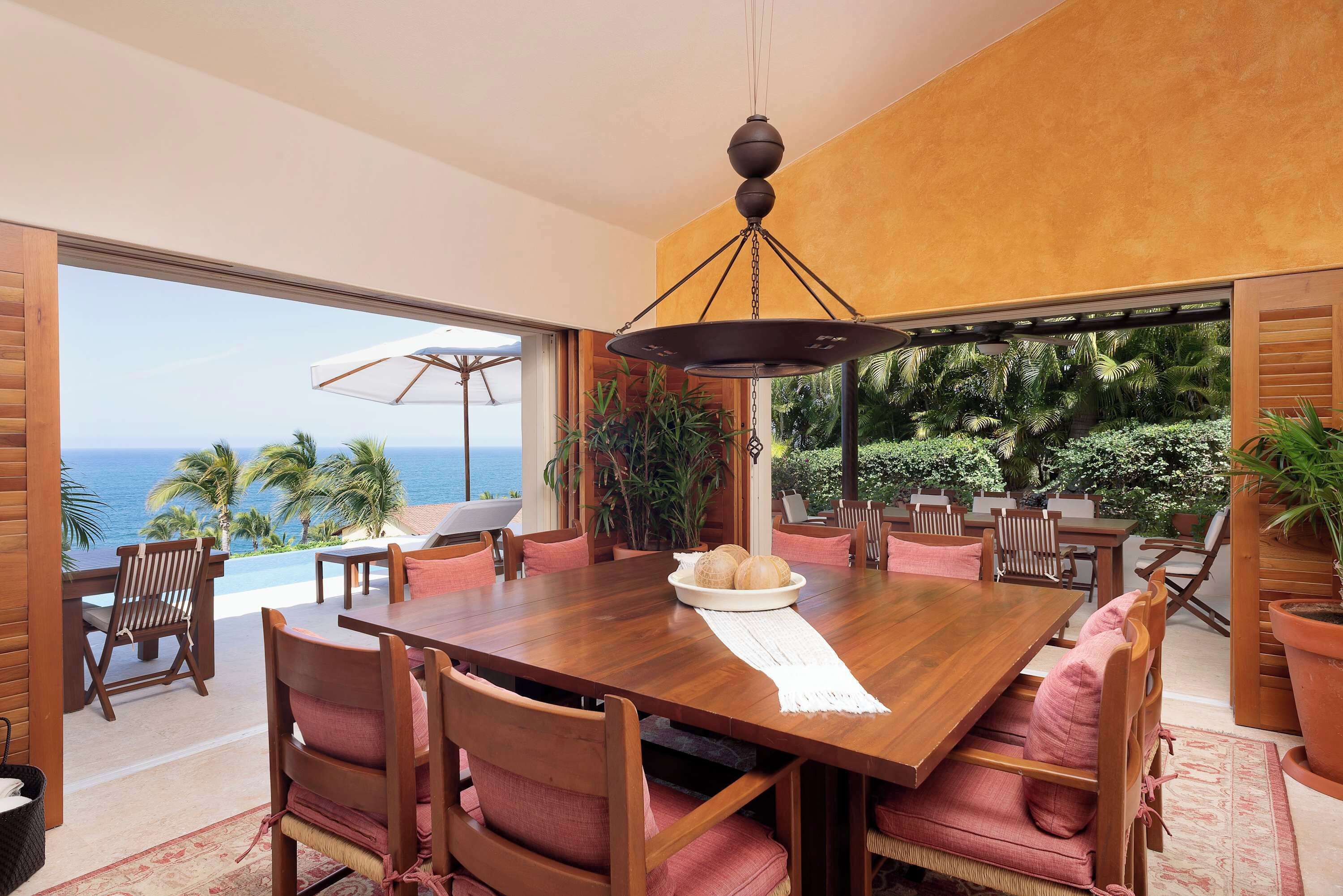 A dining area with a wooden table, chairs, and a view of the ocean.