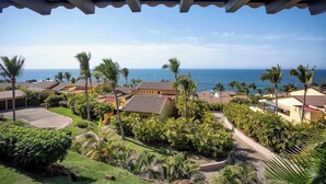 Um resort com vista para o oceano, palmeiras e uma galeria coberta.