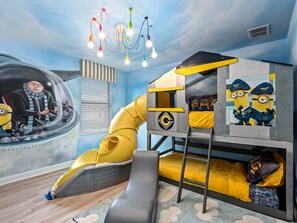 Ein Kinderzimmer mit Rutsche, Stockbett und Minion-Dekorationen.