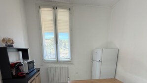 Cocina compacta con una mesa de madera, un armario negro, un microondas y un refrigerador.