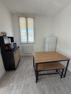 A compact kitchen with a wooden table, a black cabinet, a microwave, and a refrigerator.