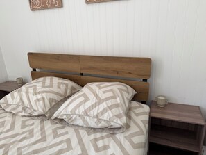 A bed with a wooden headboard, two nightstands, and a patterned bedspread.