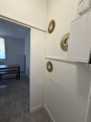 A kitchen with a white refrigerator, a wooden bench, and decorative wall mirrors.