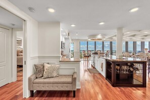 A modern kitchen with a central island, wooden flooring, and large windows offering a view. - Mansions By The Sea 1201a - Premier (Treasure Island)