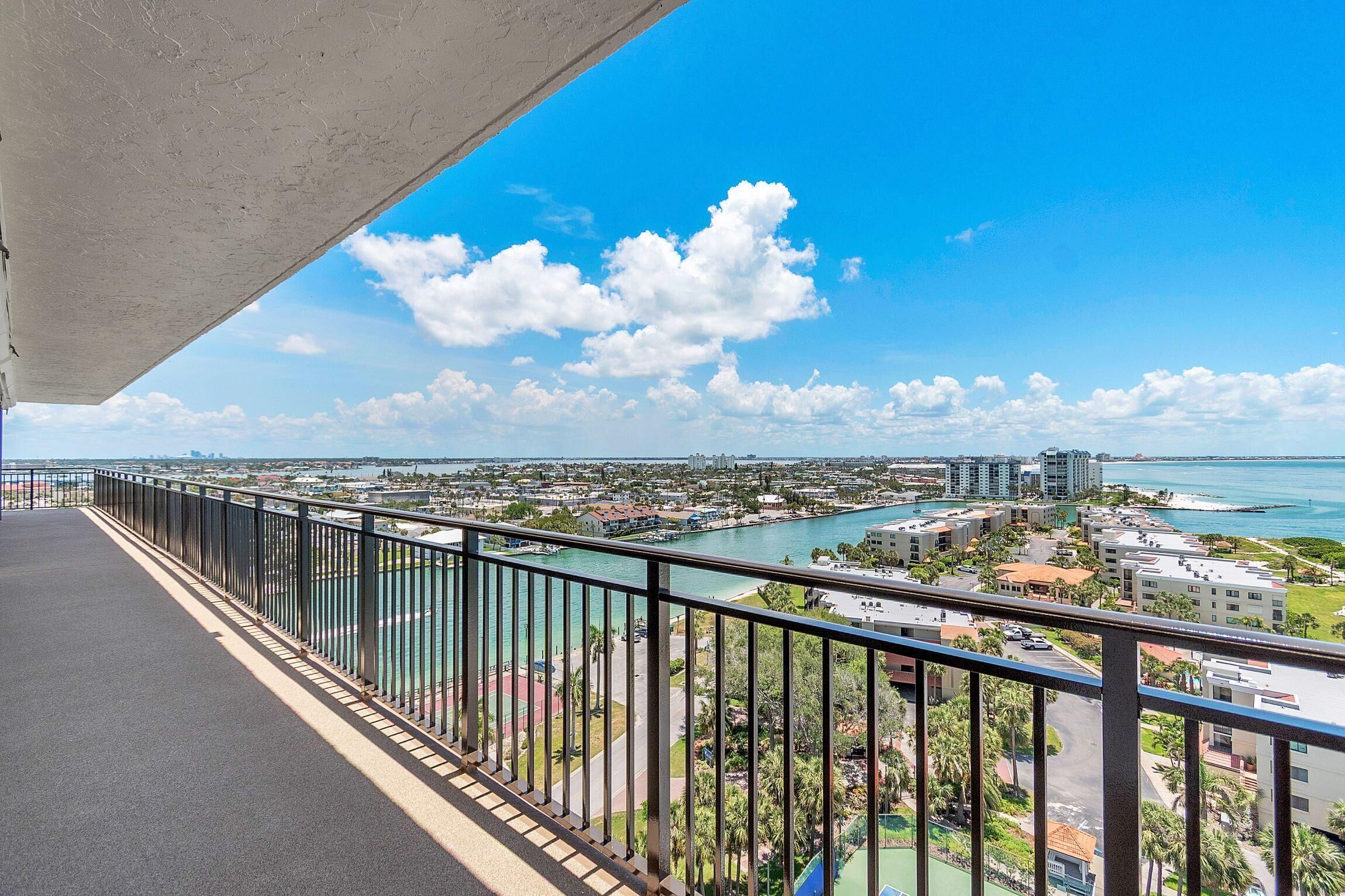 A balcony with a view of a river, buildings, and a clear sky.