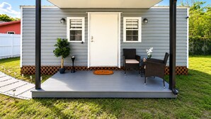 A covered porch with a white door, two windows, a small table with chairs, and a welcome mat. - Charm, comfort and an exceptional location ,  Free parking (Miramar)