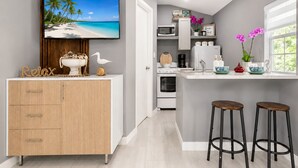 A modern kitchen with a TV, wooden cabinets, a microwave, and bar stools. - Charm, comfort and an exceptional location ,  Free parking (Miramar)