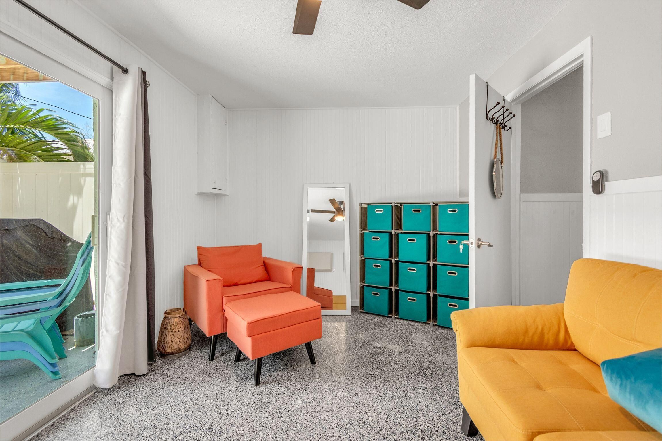 A room with a sofa, a chair, a cabinet, and a door.