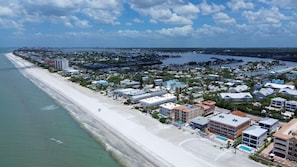 An aerial view of a coastal town with a beach, buildings, and a marina. - Beach Blast Retreat (Indian Rocks Beach)