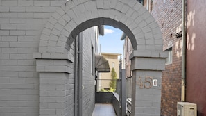 A narrow alleyway with a brick archway, a small balcony with a plant, and a building with the number 45. - The 450 Collection Double Bay Stays Suite 3 (Double Bay)