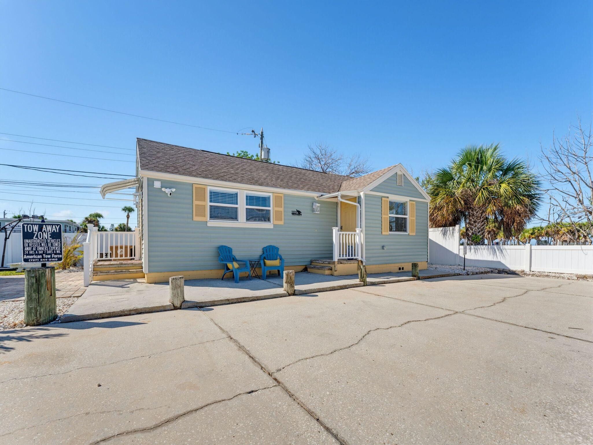 A small, single-story building with a porch and two blue chairs outside.