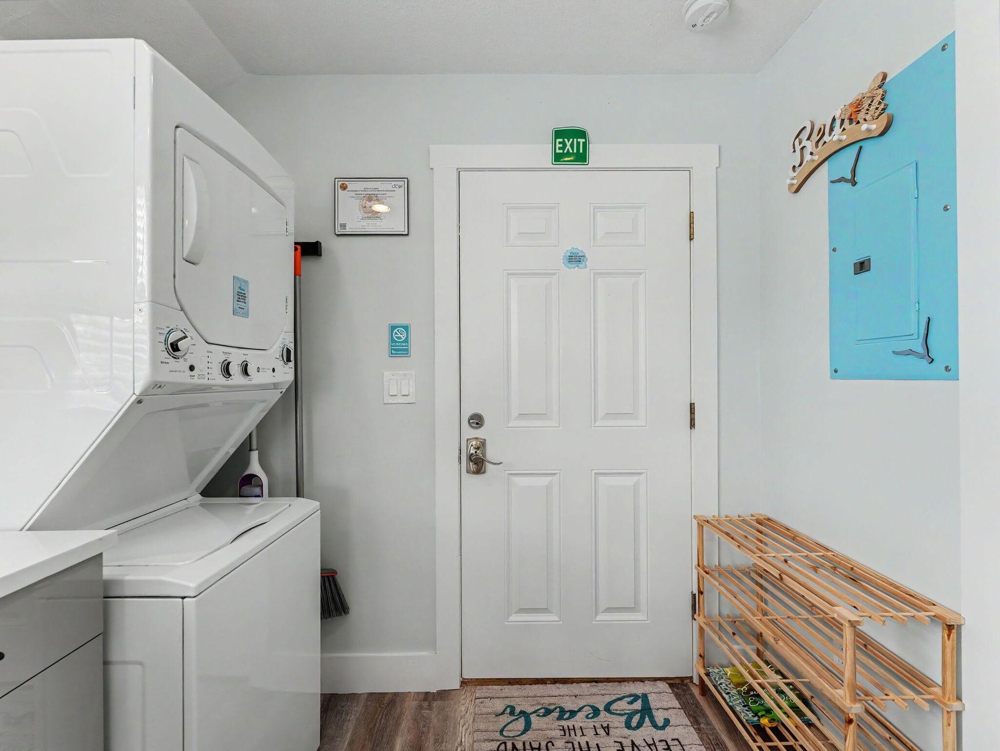 A laundry room with a white door, an exit sign, and a blue wall with a sign.