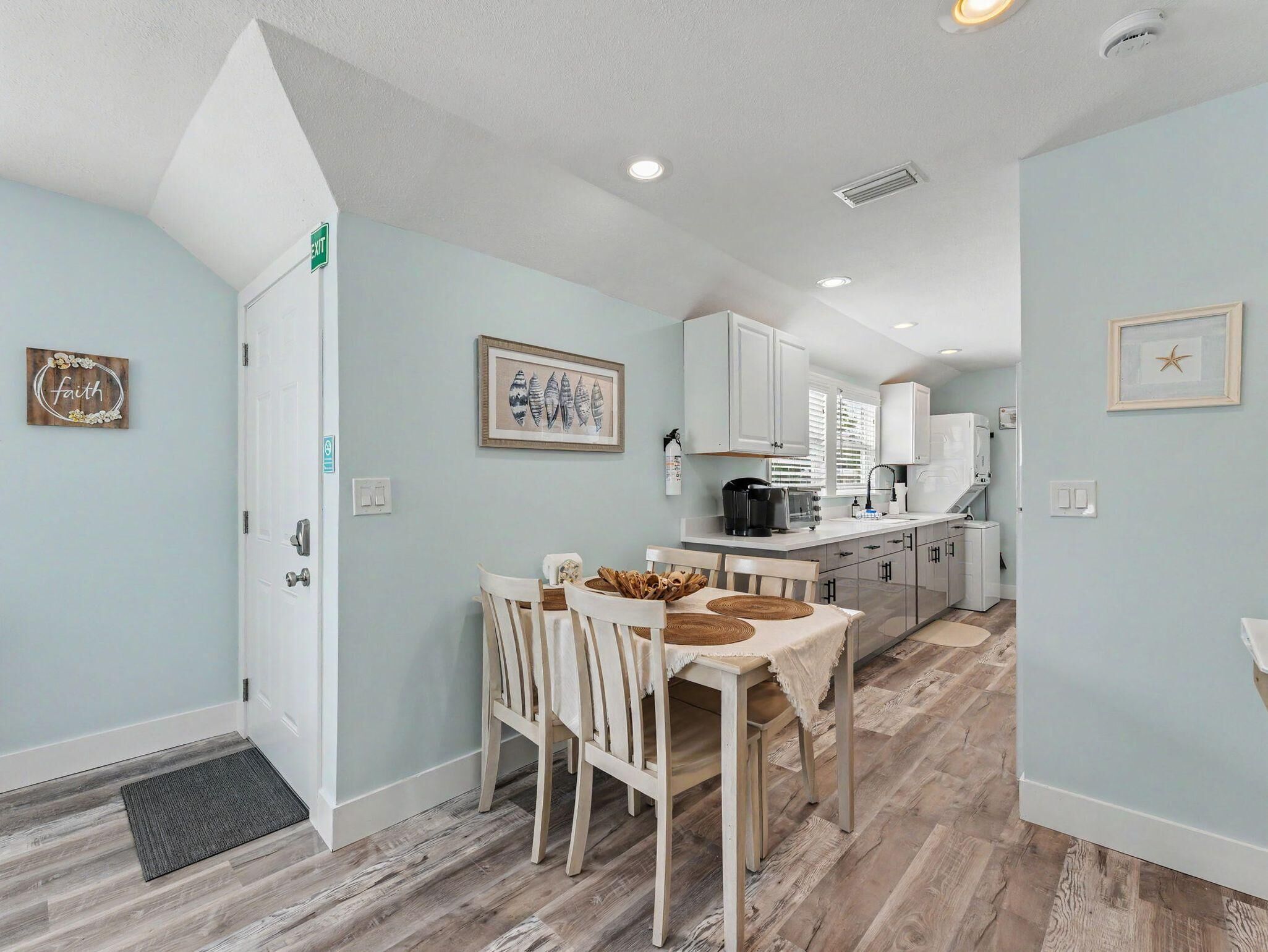 A modern kitchen with white cabinets, a dining table with chairs, and a small island.