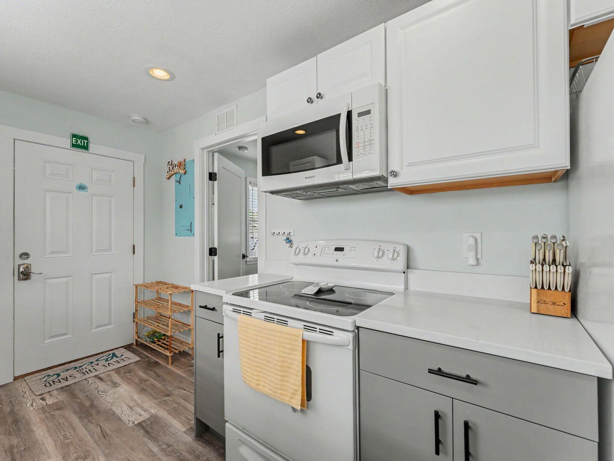 A kitchen with white cabinets, a microwave, a stove, and a sink.