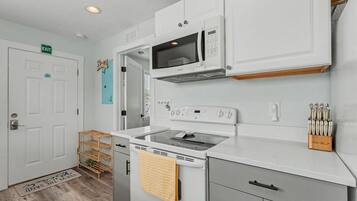 A kitchen with white cabinets, a microwave, a stove, and a sink.