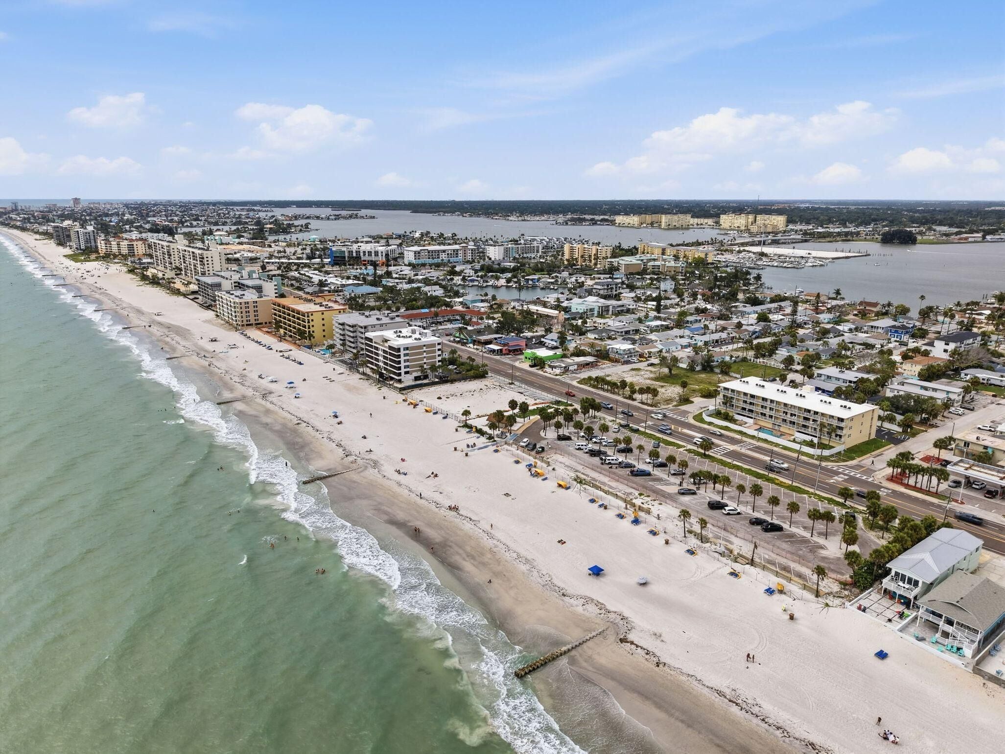 An aerial view of a coastal city with a beachfront, buildings, and roads.