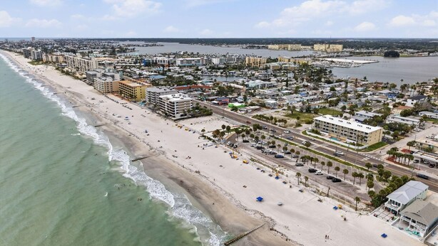 An aerial view of a coastal city with a beachfront, buildings, and roads. - Sunset Paradise (Madeira Beach)
