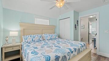 A bedroom with a bed, nightstand, lamp, and a ceiling fan.
