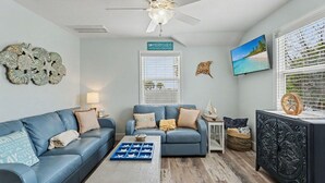 A living room with two sofas, a coffee table, a TV, and decorative wall art. - Sunset Paradise (Madeira Beach)