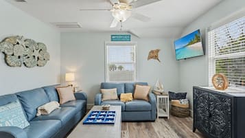 A living room with two sofas, a coffee table, a TV, and decorative wall art.