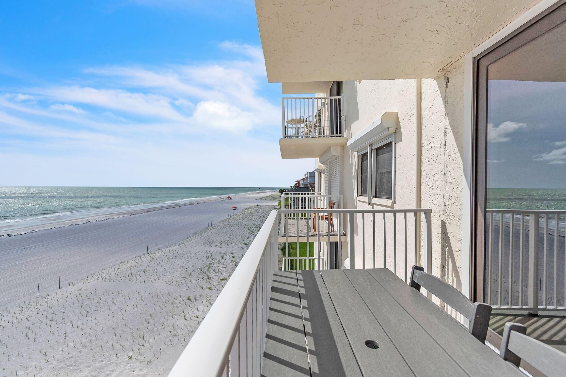 Un balcon donnant sur la plage, une table en bois et une rambarde.
