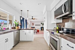 Eine moderne Küche mit weißen Schränken, einer Mikrowelle, einem Backofen und einem Deckenventilator.