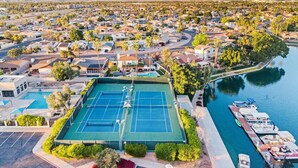 Vue aérienne d’un quartier résidentiel avec un court de tennis, une marina et une rivière.