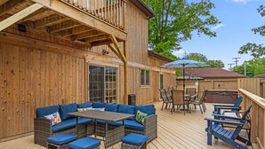 Een houten terras met een bank, stoelen en een tafel.
