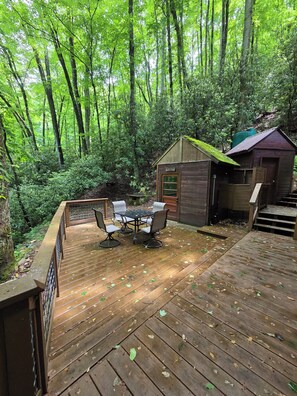 Una terraza de madera con una mesa y sillas, rodeada de un bosque.