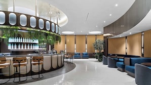 A modern lobby with a bar area, seating, and a large plant. - Luxury E11EVEN Studio 50th Floor with Elite Amenities (Miami)