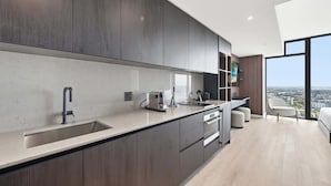 A modern kitchen with a large island, built-in appliances, and a city view through large windows. - Luxury E11EVEN Studio 50th Floor with Elite Amenities (Miami)