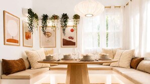 Un comedor moderno con una mesa de madera, asientos acolchados y cuadros en las paredes.